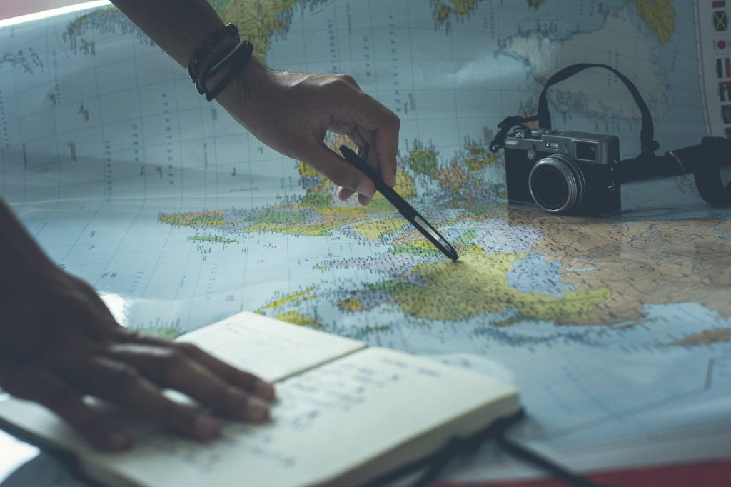 A hand holding a pen pointing at a map