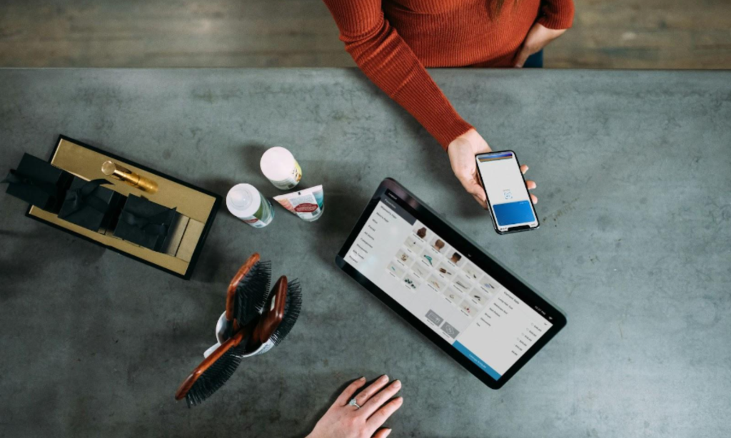 A man and a woman working together, one on a laptop and the other on a phone.