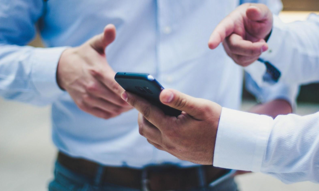 Two men are using their mobile phones together