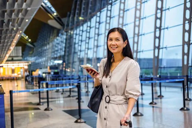 traveler standing in a line at the airport with her passport in her hands